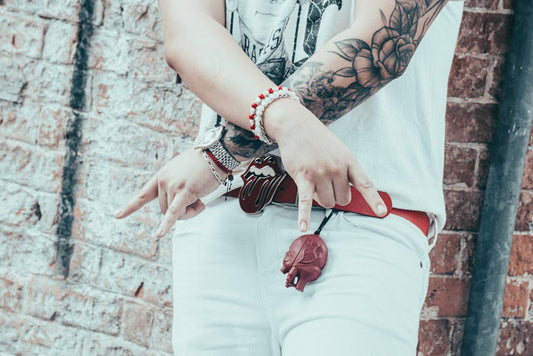 Stylish tattooed individual showcasing rock style fashion near urban brick wall.